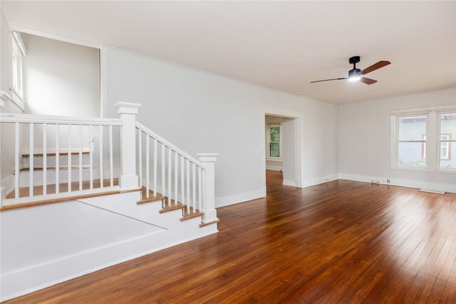 Unfurnished room with a ceiling fan, wood-type flooring, ornamental molding, stairs, and baseboards | Image 32