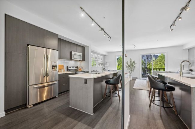 Kitchen with appliances with stainless steel finishes, track lighting, a sink, modern cabinets, and a kitchen island with sink | Image 14