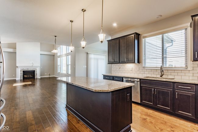 kitchen with dark brown cabinets, stainless steel dishwasher, a sink, and tasteful backsplash | Image 21