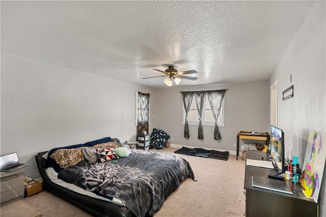 Carpeted bedroom with ceiling fan and a textured ceiling | Image 25