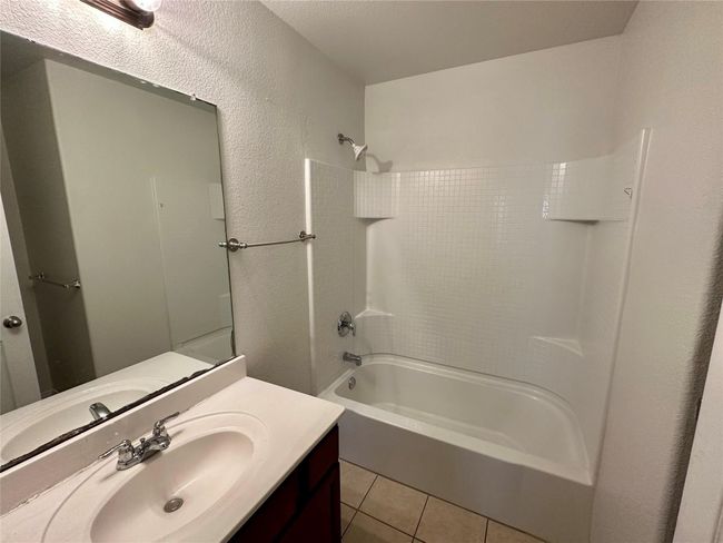 Bathroom featuring tile patterned floors, tub / shower combination, a textured wall, and vanity | Image 9