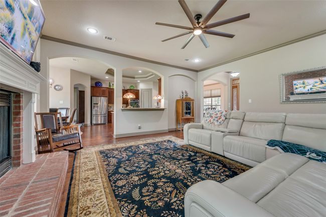 Living area with ceiling fan, a fireplace, arched walkways, crown molding, and recessed lighting | Image 15