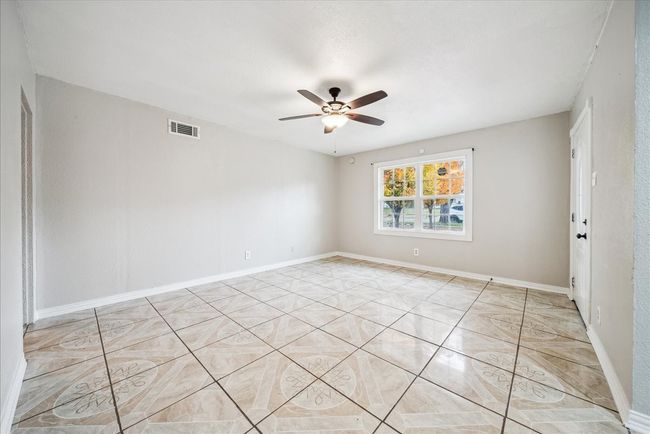 Empty room with ceiling fan and light tile patterned flooring | Image 5