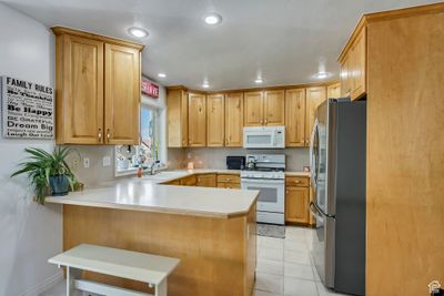 Kitchen with white appliances, sink, kitchen peninsula, and light tile patterned flooring | Image 2