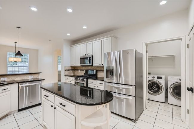 Kitchen with appliances with stainless steel finishes, washer and clothes dryer, decorative backsplash, arched walkways, and recessed lighting | Image 11