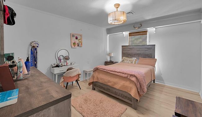 Bedroom with light wood finished floors, crown molding, and a ceiling fan | Image 22