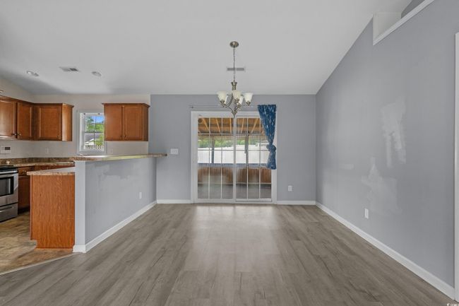Kitchen with wood finished floors, electric range, a chandelier, and baseboards | Image 16