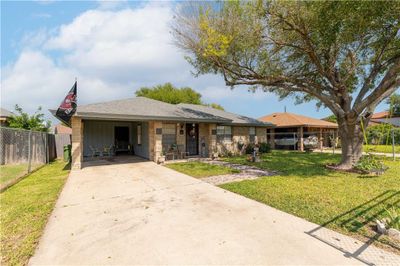 Ranch-style house with a front lawn and a carport | Image 2