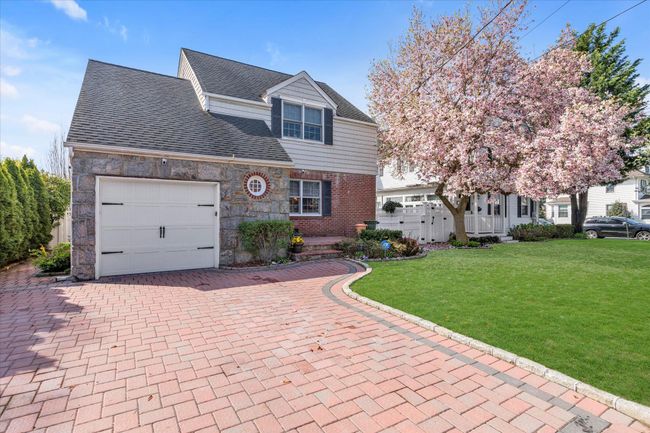 View of front of house with decorative driveway, a front lawn, stone siding, a shingled roof, and a garage | Image 19