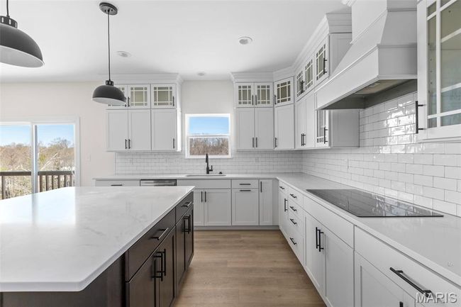 Kitchen featuring black electric stovetop, custom range hood, backsplash, healthy amount of natural light, and recessed lighting | Image 16