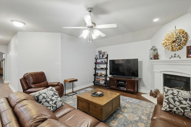 Living area with a ceiling fan, wood finished floors, a glass covered fireplace, and vaulted ceiling | Image 23