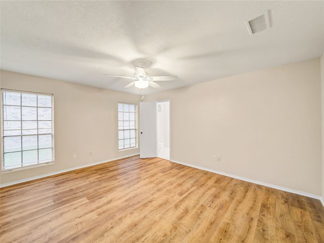 Empty room featuring baseboards, light wood finished floors, healthy amount of natural light, and a textured ceiling | Image 11