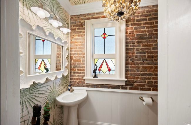 Half bathroom with a wainscoted wall, healthy amount of natural light, brick wall, and a chandelier | Image 36