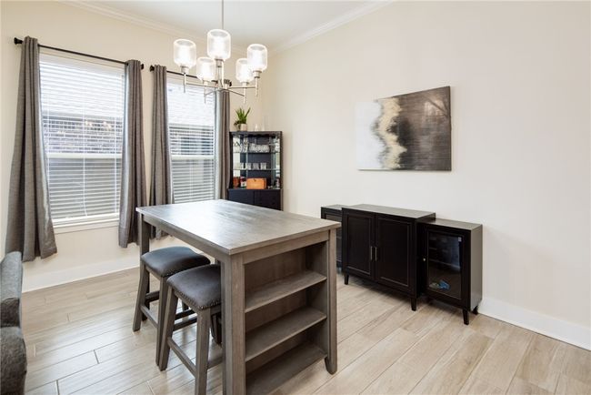 Dining area with a chandelier, baseboards, crown molding, and light wood-style floors | Image 10