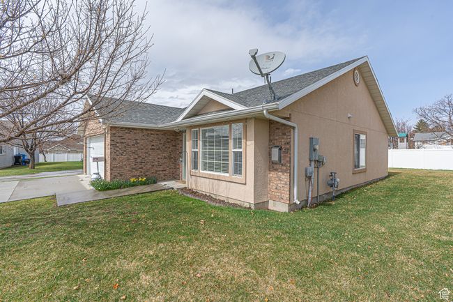 View of property exterior featuring a yard, fence, concrete driveway, and roof with shingles | Image 27