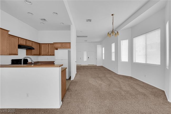 Kitchen featuring light colored carpet, under cabinet range hood, visible vents, and freestanding refrigerator | Image 6