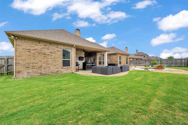 Rear view of property featuring ceiling fan, brick siding, an outdoor living space, a patio, and a chimney | Image 4
