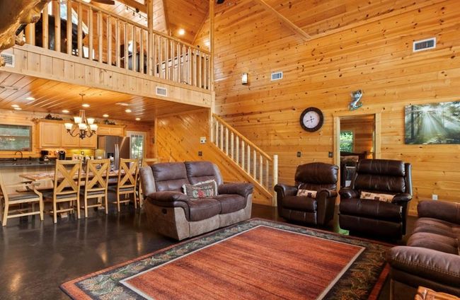 Living area with wooden walls, stairs, a towering ceiling, a chandelier, and wood ceiling | Image 8