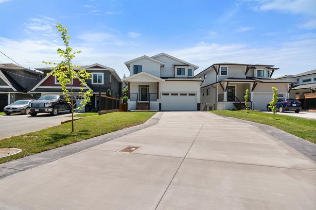 Traditional-style home with an attached garage, driveway, a front lawn, and a residential view | Image 40