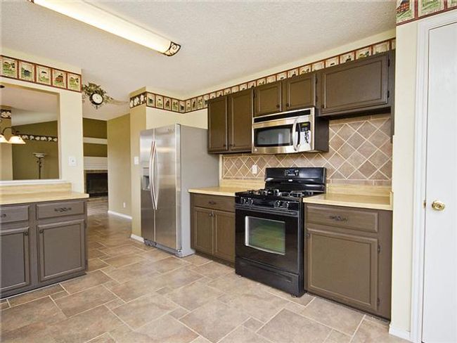 Kitchen featuring tasteful backsplash, stainless steel appliances, light countertops, stone finish flooring, and baseboards | Image 4