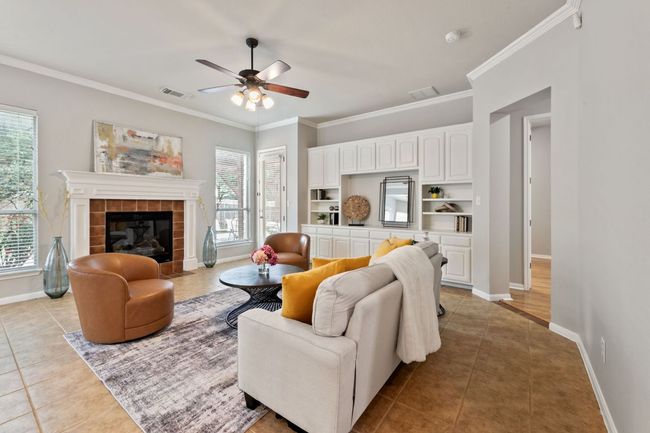Living area with light tile patterned floors, plenty of natural light, ornamental molding, a tile fireplace, and a ceiling fan | Image 18