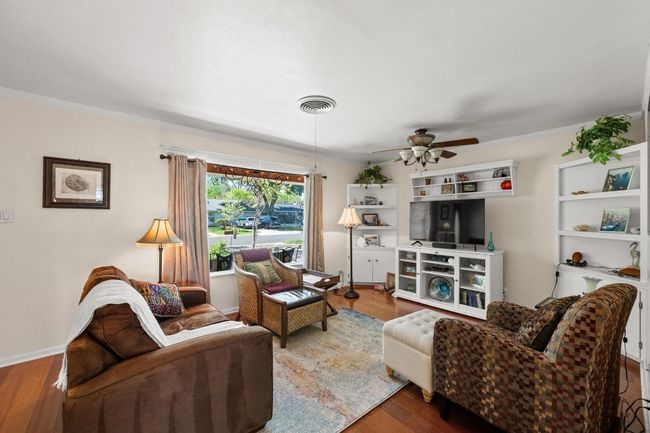 Living area with wood finished floors, ceiling fan, and visible vents | Image 4