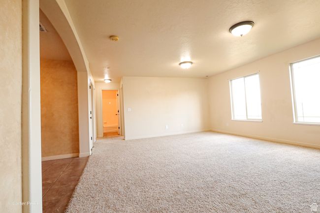 Unfurnished room featuring arched walkways, light carpet, and light tile patterned floors | Image 7