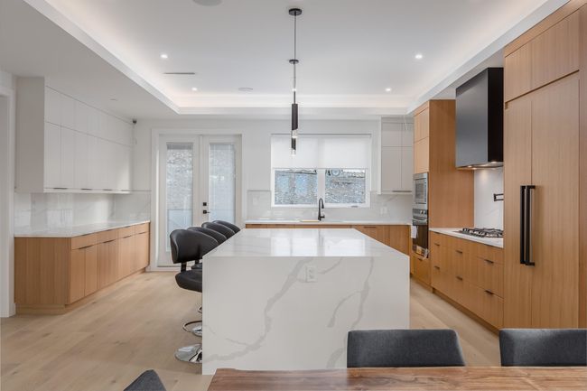 Kitchen featuring oven, modern cabinets, a sink, a center island, and wall chimney exhaust hood | Image 4