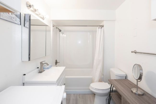 Bathroom featuring vanity, shower / bath combination with curtain, and wood finished floors | Image 5