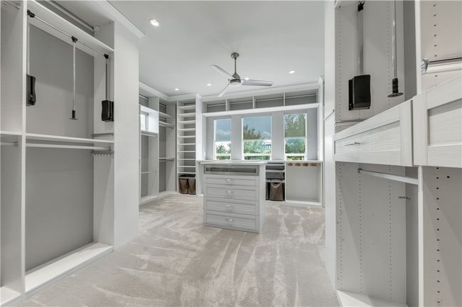 Spacious closet with a ceiling fan and light carpet | Image 17