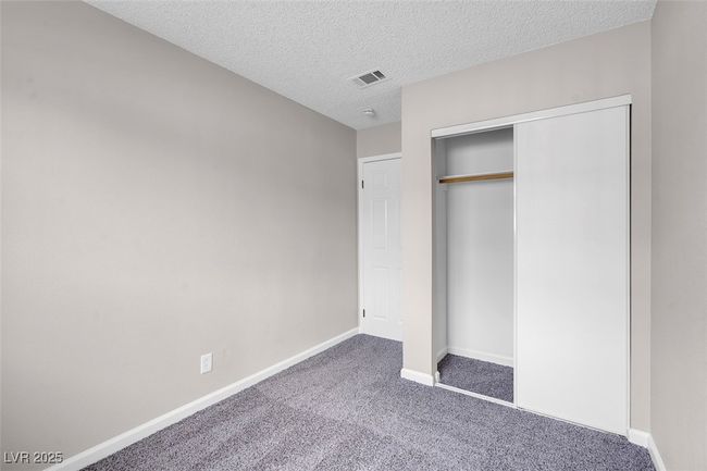 Unfurnished bedroom with carpet flooring, a textured ceiling, baseboards, visible vents, and a closet | Image 26