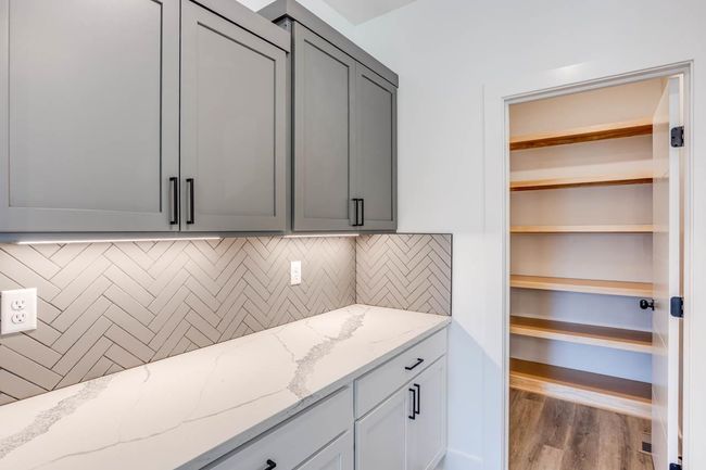 Kitchen featuring light stone counters, tasteful backsplash, wood finished floors, and gray cabinetry | Image 11