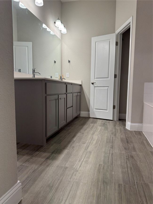 Bathroom featuring vanity, wood-type flooring, and a washtub | Image 6
