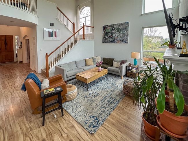 Living room featuring a towering ceiling, wood finished floors, arched walkways, and stairs | Image 10
