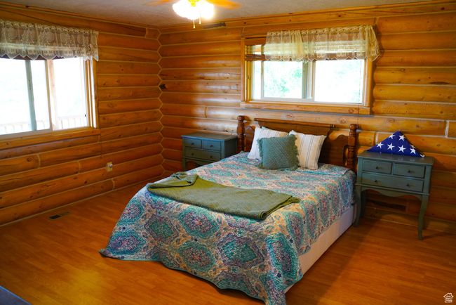 Bedroom featuring wood finished floors, log walls, and multiple windows | Image 14