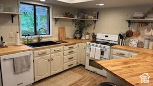 Kitchen with double oven range, open shelves, butcher block countertops, recessed lighting, and a sink | Image 9