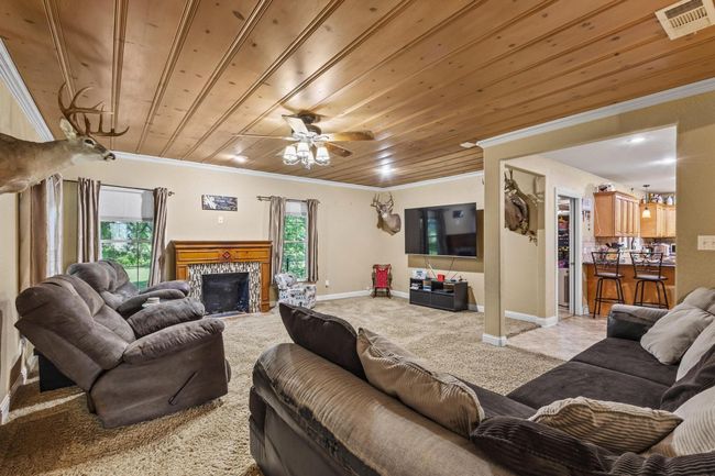 Living room with wooden ceiling, baseboards, crown molding, and visible vents | Image 4