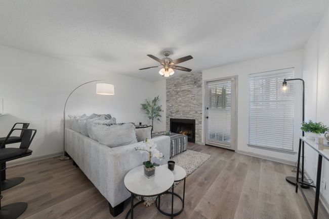 Living room with ceiling fan, wood finished floors, and a fireplace | Image 10