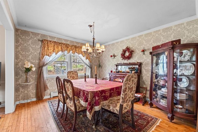Dining room with a chandelier, hardwood / wood-style floors, a baseboard heating unit, and wallpapered walls | Image 8