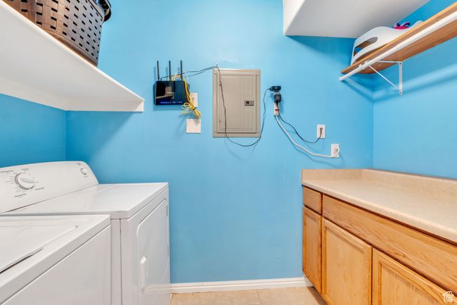 Washroom featuring electric panel, washer and clothes dryer, and light tile patterned floors | Image 13