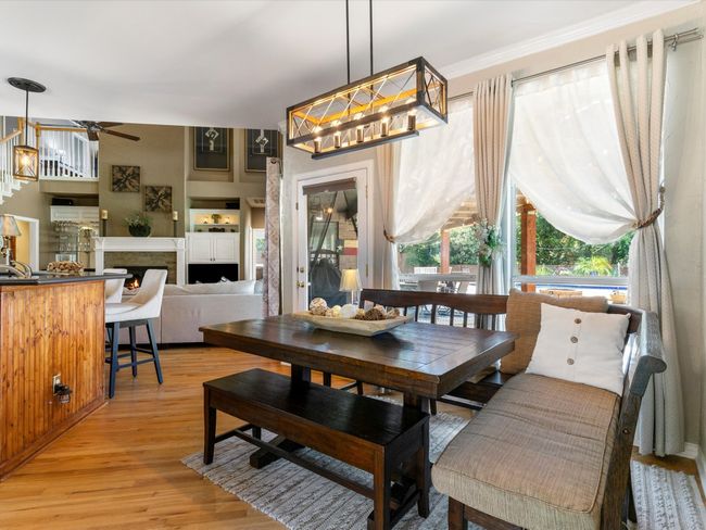 Dining space featuring a ceiling fan, light wood-type flooring, and a lit fireplace | Image 13
