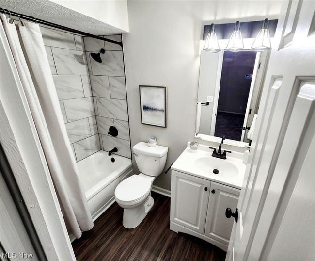 Full bathroom featuring toilet, large vanity, shower / bath combo, and hardwood / wood-style flooring | Image 18