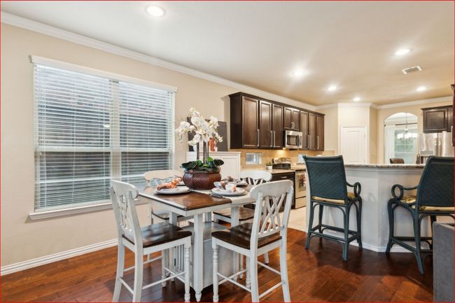 Dining room featuring dark wood-style floors, crown molding, recessed lighting, and arched walkways | Image 4
