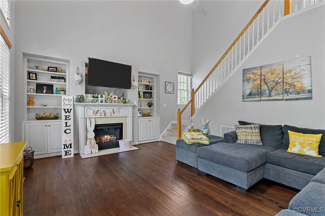 Living area featuring dark wood-style floors, stairs, a high end fireplace, and a high ceiling | Image 18