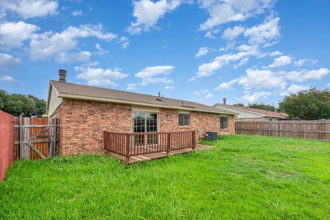 Rear view of property featuring brick siding, a fenced backyard, and a deck | Image 21