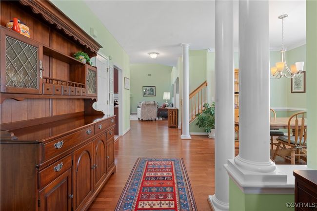Hallway featuring wood finished floors, stairs, ornate columns, a chandelier, and crown molding | Image 6