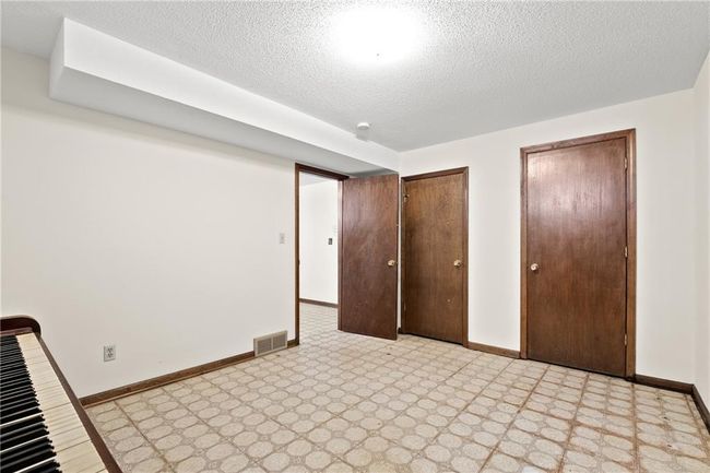 Unfurnished bedroom featuring light flooring, multiple closets, baseboards, and a textured ceiling | Image 22