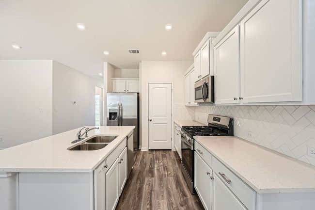 Kitchen featuring visible vents, dark wood finished floors, a sink, stainless steel appliances, and tasteful backsplash | Image 13