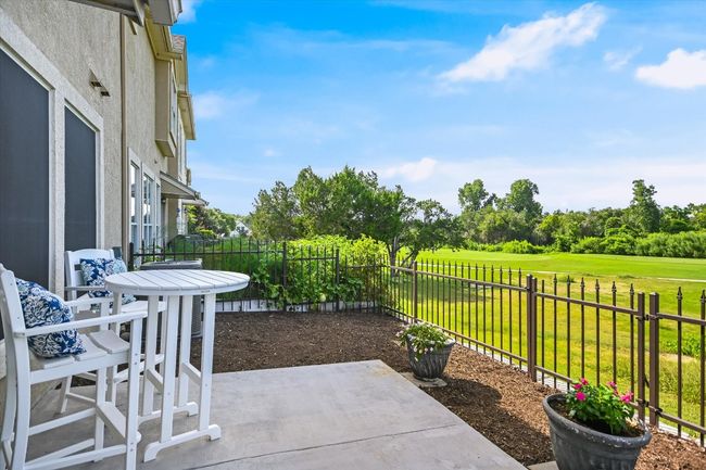 Fenced backyard with a patio area, view of golf course, and view of scattered trees | Image 14