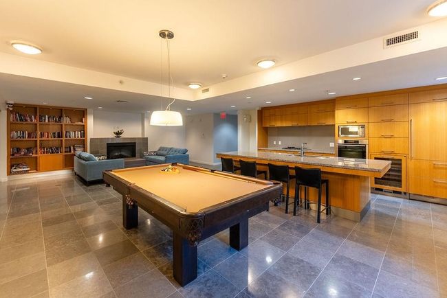 Recreation room with spacious kitchen , a tiled fireplace, a pool table, wine cooler, small library and recessed lighting | Image 35